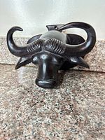 front view of carved wood buffalo head showing horns and facial details