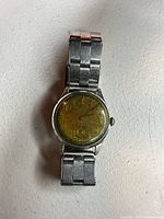 Front view showing yellow patina dial, scratched crystal, bracelet attached