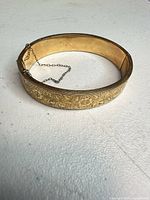 Full view of gold tone bangle showing oval shape and interior
