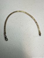 Full view of gold-tone flat snake bracelet with lobster clasp