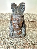Front view of carved wooden bust with feathered headdress