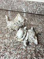 Front view of both porcelain cat figurines on granite surface