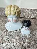 Both porcelain busts side by side showing relative sizes and mounting holes