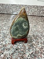 Front view of polished stone on stand showing green gray face with circular pattern