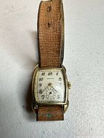 Front view of rectangular Reyco wristwatch with cream dial and leather strap