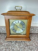 Front view of Seiko wood mantel clock showing case, handle, dial and glass door