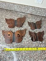 Four wooden wall birds laid out on countertop with tape for scale