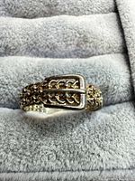 Front view showing buckle motif and chain-link texture