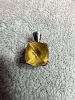 Front view of sterling silver pendant with yellow glass stone