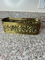 Front and side view of brass planter showing floral embossing