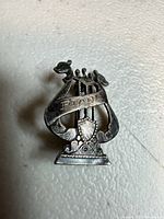 Front view of sterling lyre brooch showing banner, shield and animal head finials