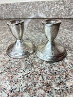 Front perspective of both sterling candlesticks showing form and engraved decoration