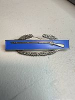 front view of sterling Combat Infantry Badge showing blue enamel, rifle and wreath detail