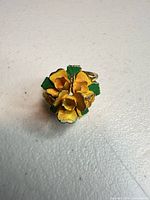 Top view showing yellow enamel flowers and green leaves on gold-tone ring