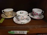 Three teacup and saucer sets on shelf