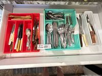Overview of red and turquoise organizer trays filled with flatware and steak knives