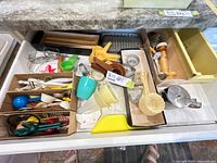 Drawer with assorted utensils including measuring cups, funnels, whisks, pastry blender, melon baller, scrapers, tart molds