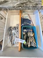Drawer view showing bin of assorted flatware and bag of spoons