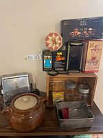 Overall view showing bean pot, toaster, tins, jars, loaf pan, doughnut maker and crate
