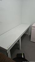 Full view of long white workbench table along wall