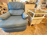 Blue recliner beside cream side table with glass top