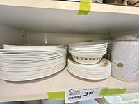 Stacks of plain white dinner plates, side plates and bowls on shelf