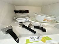 Cabinet view showing Corning Ware casseroles, Fire-King dishes and Rena Ware handles