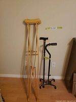 Pair of wooden crutches, black single-tip cane, black quad cane