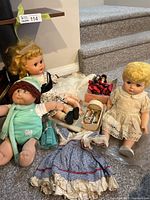 Overall group of dolls, cradle set, extra dress visible