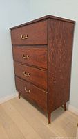 Front view of wooden 4-drawer dresser showing drawer arrangement and brass pulls