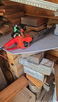 Left side view of red Craftsman corded electric chainsaw resting on wood, showing full bar and body