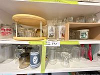 Shelves with assorted clear glasses, tumblers, beer mugs, wooden rotating holder