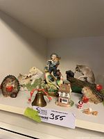 Shelf view showing majority of figurines including hedgehogs, raccoon, bird, farm child, wolves