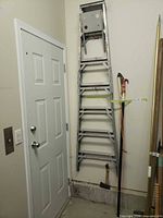 Ladder and pole pruner stored vertically in garage