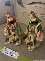 Front view of both ceramic figurines showing dresses, dogs and overall design