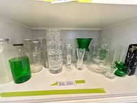 Shelf view showing mixed clear and green glass vases, jars, containers
