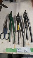 Group view of four metal shears on workbench