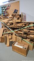 Overall view of stacked wood pieces in varying sizes and shapes on shelf with box below