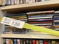 Shelf section showing approximately twenty music CD spines in jewel cases, label tag 139 attached