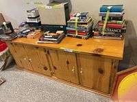 Front view of long pine cupboard with books on top (books not included)