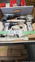 Box containing three pneumatic tools with accessories visible