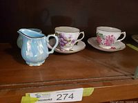 Sadler blue lustre creamer and two floral teacups with saucers displayed on shelf