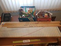 Overall lot showing cutting board, yardsticks, boxes of sewing notions