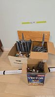 Boxes containing assorted grey shelf brackets and white hook supports