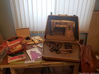Singer sewing machine in case with foot pedal and boxed accessories visible
