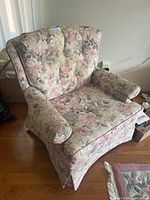 Front view of floral upholstered armchair showing seat, arms, tufted back and skirted base