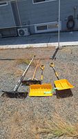 All four tools laid out: roof rake, push broom, two snow shovels