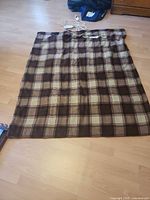Full view of plaid electric blanket laid flat showing size and controller
