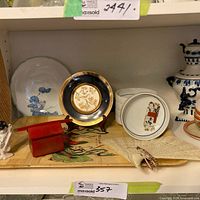 Shelf with plates, fan, tray, figurine, red lacquer box and lidded bowl