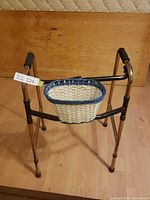 Front view of bronze-tone folding walker with basket attached
